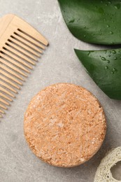 Photo of Solid shampoo bar, monstera leaf and comb on grey table, flat lay