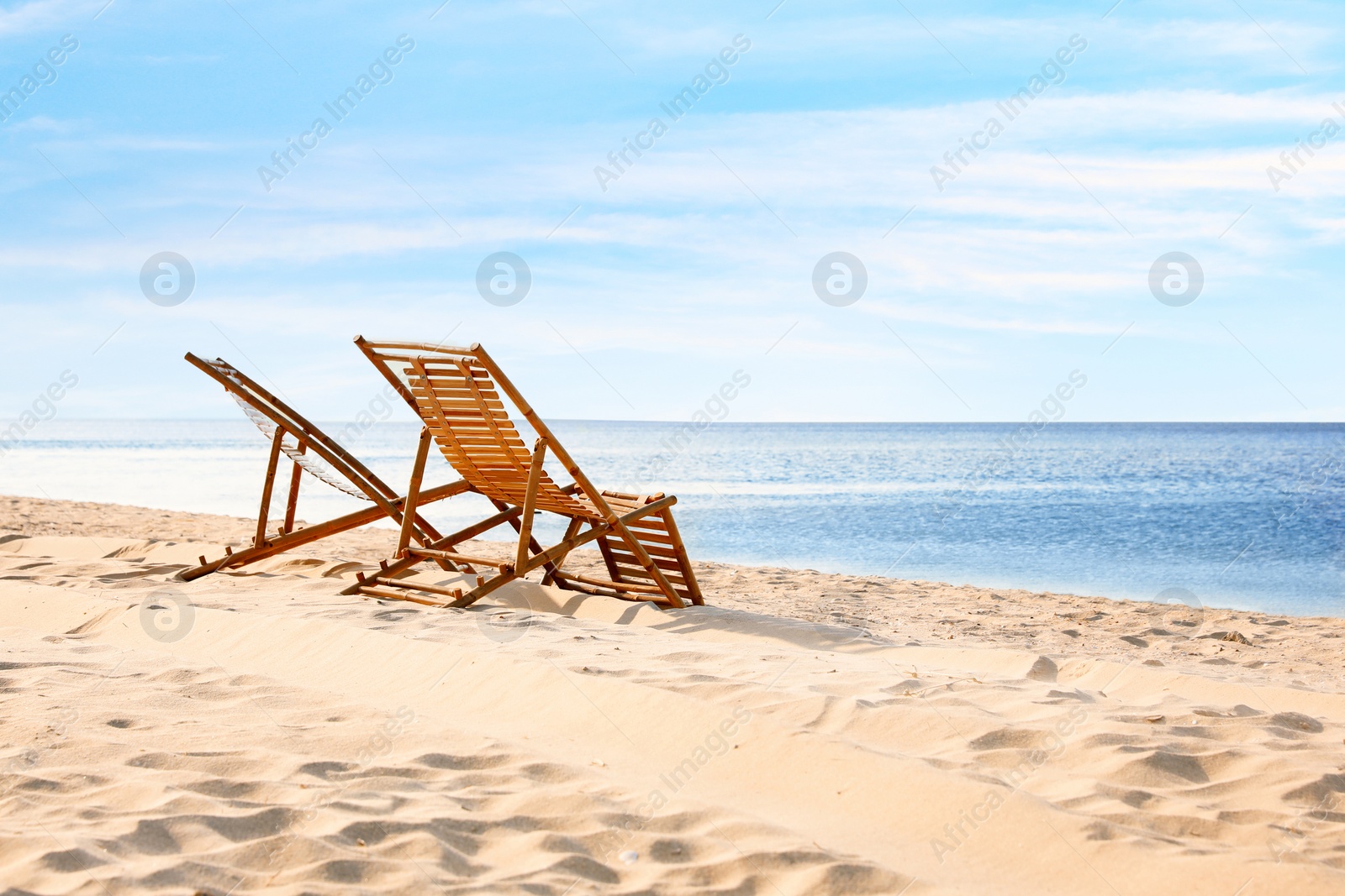 Photo of Wooden deck chairs on sandy beach near sea