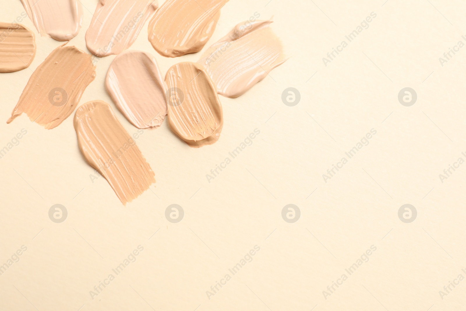 Photo of Samples of skin foundation on beige background. Space for text