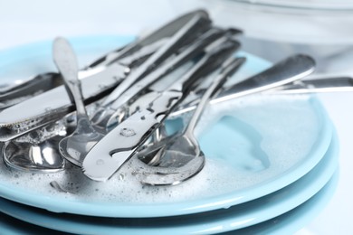 Photo of Forks, knives, plates and spoons in foam, closeup