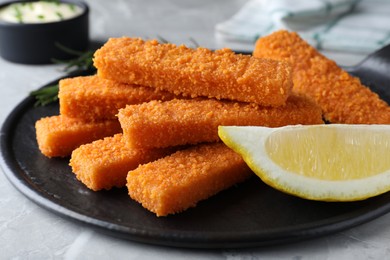 Photo of Fresh breaded fish fingers and lemon served on light grey table, closeup