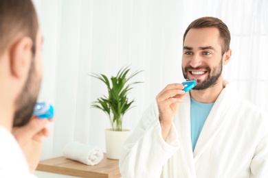 Young man using teeth whitening device at home