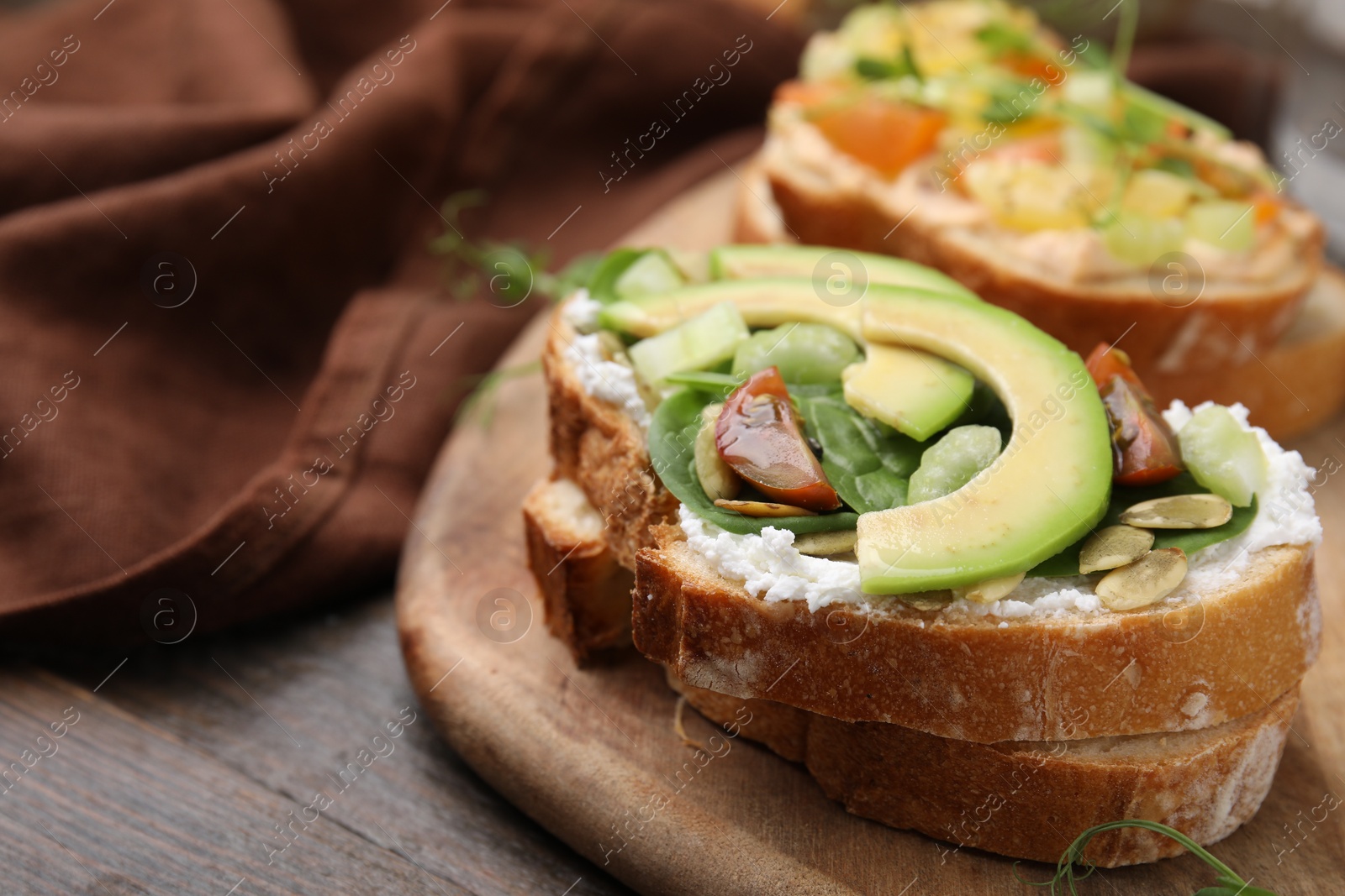 Photo of Tasty vegan sandwiches with vegetables on wooden table, closeup. Space for text