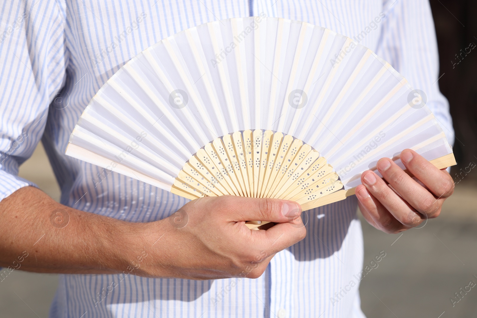 Photo of Man with white hand fan outdoors, closeup