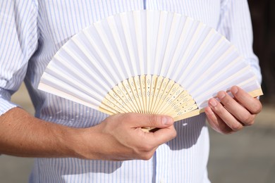 Photo of Man with white hand fan outdoors, closeup