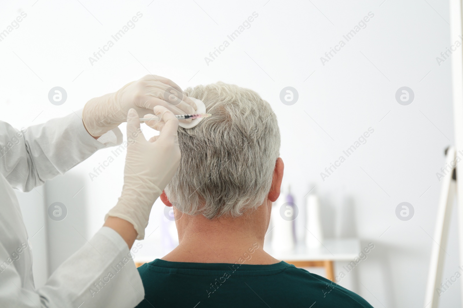 Photo of Senior man with hair loss problem receiving injection in salon