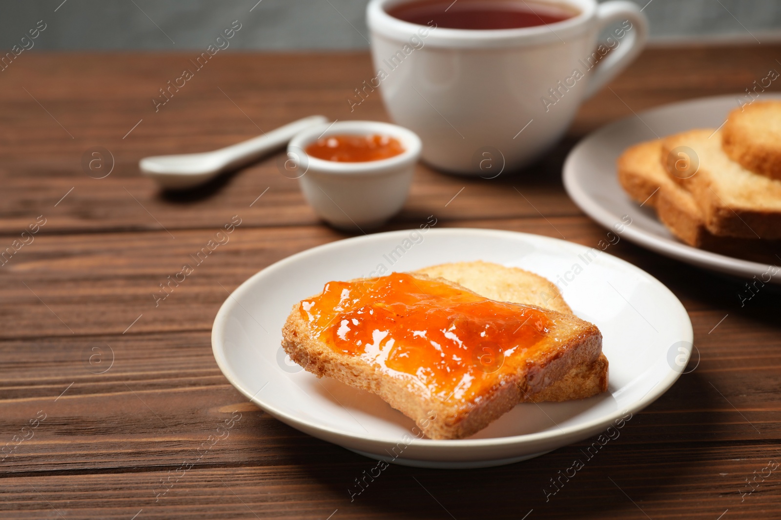 Photo of Toasts with jam and cup of tea on wooden table