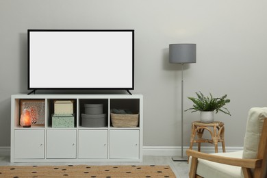 Image of Modern TV on cabinet near light wall indoors. Interior design