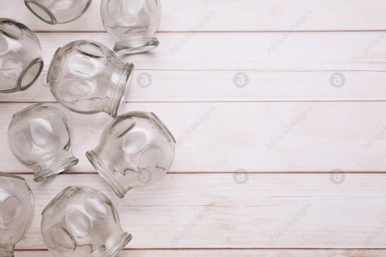 Photo of Glass cups on white wooden table, flat lay with space for text. Cupping therapy