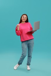 Young woman with modern laptop on light blue background