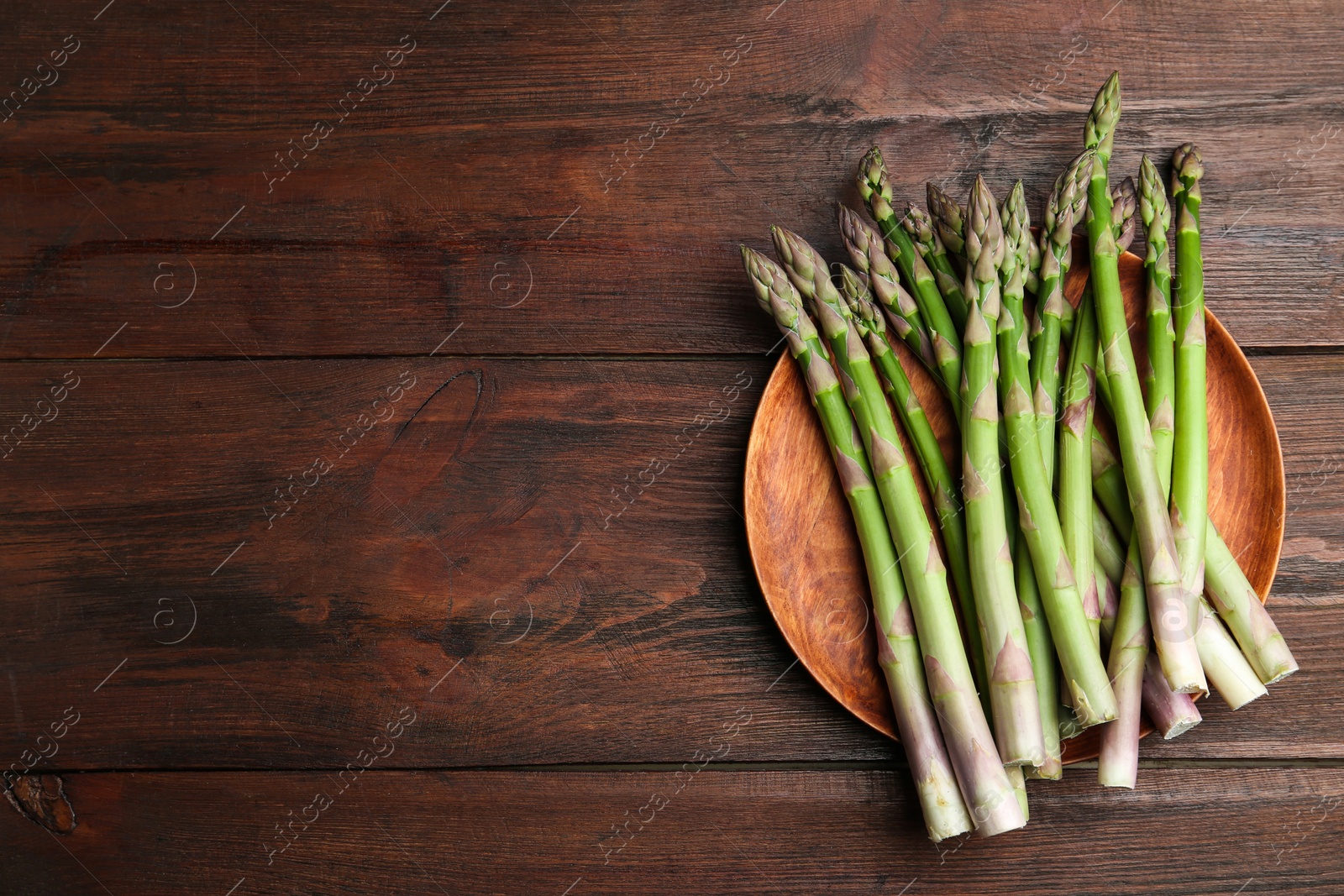 Photo of Fresh raw asparagus on wooden table, top view. Space for text