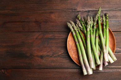 Fresh raw asparagus on wooden table, top view. Space for text