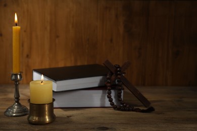 Photo of Church candles, Bible, cross and rosary beads on wooden table
