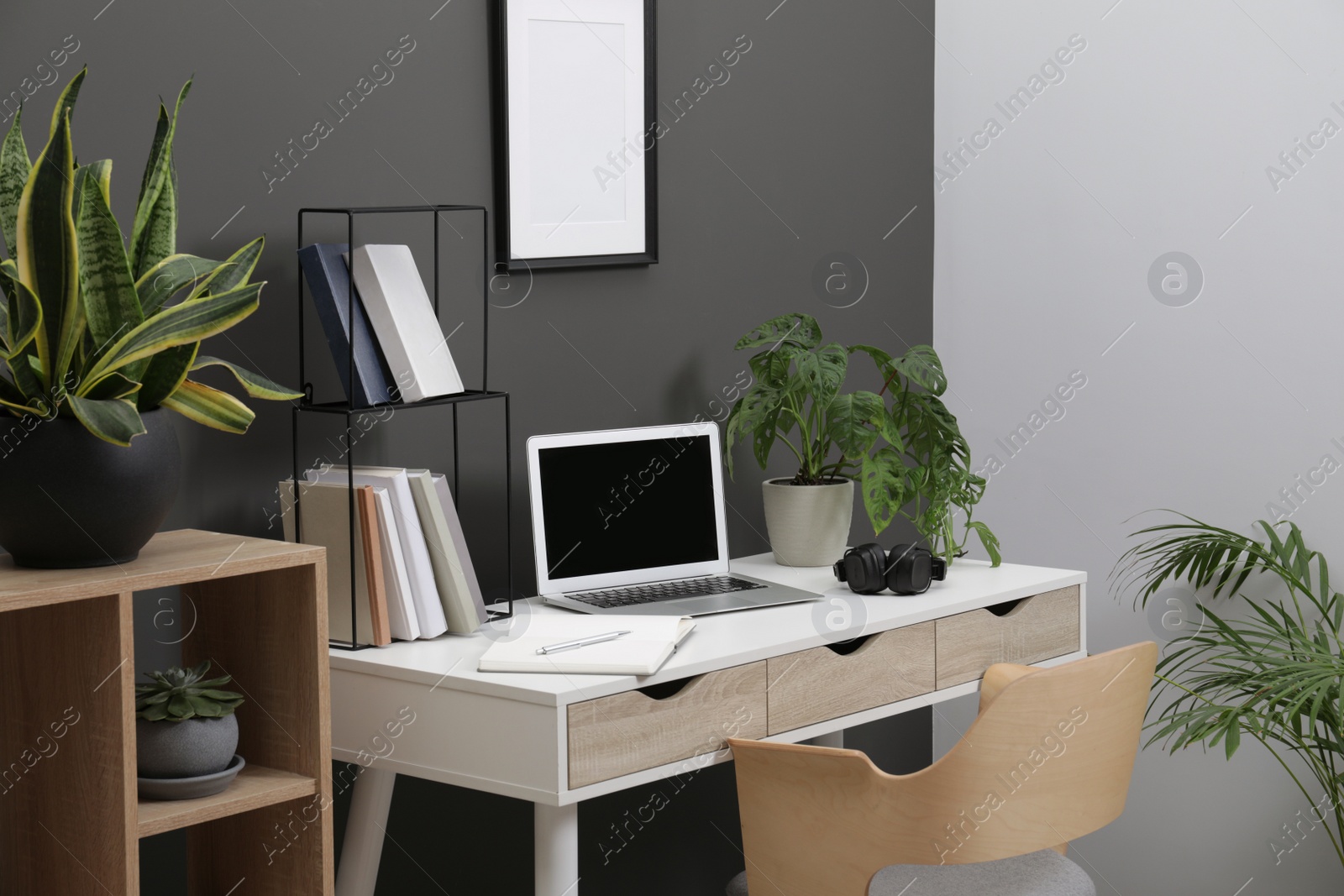 Photo of Workplace with laptop, stationery on desk and chair in home office