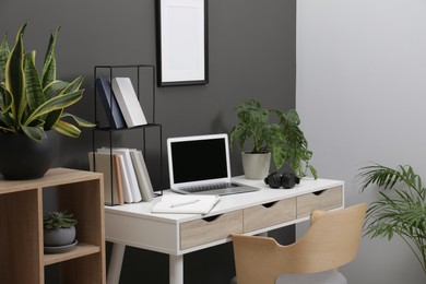 Workplace with laptop, stationery on desk and chair in home office