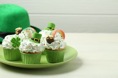 Photo of St. Patrick's day party. Tasty festively decorated cupcakes on white table, closeup. Space for text