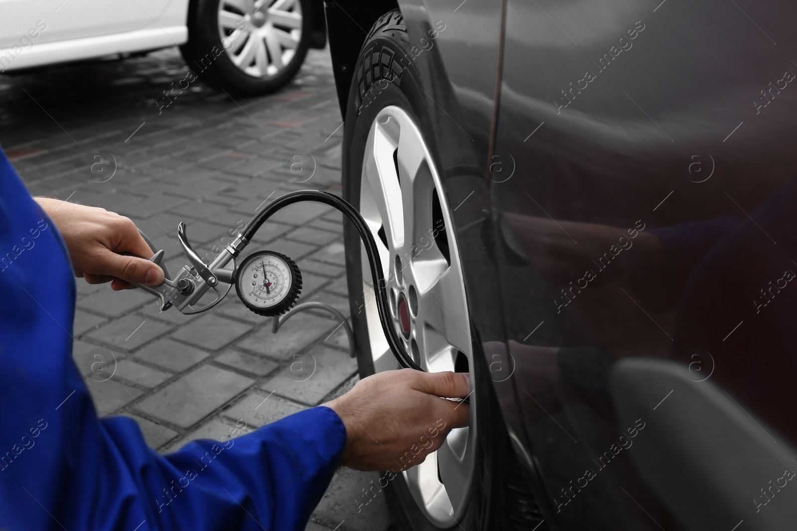 Photo of Mechanic checking tire air pressure at car service, closeup