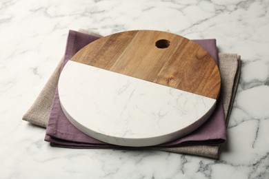 Photo of Serving board and napkins on white marble table, closeup