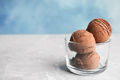 Glass of chocolate ice cream on grey table, space for text