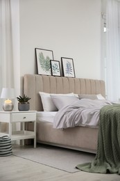 Photo of Bed with stylish grey linens near white wall in room