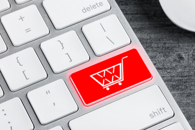 Modern computer keyboard with cart symbol on table, closeup view. Internet shopping