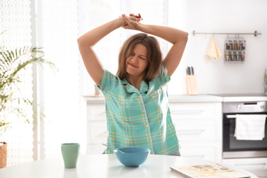 Sleepy young woman stretching at home in morning