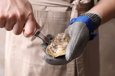 Photo of Man opening fresh oyster with knife, closeup