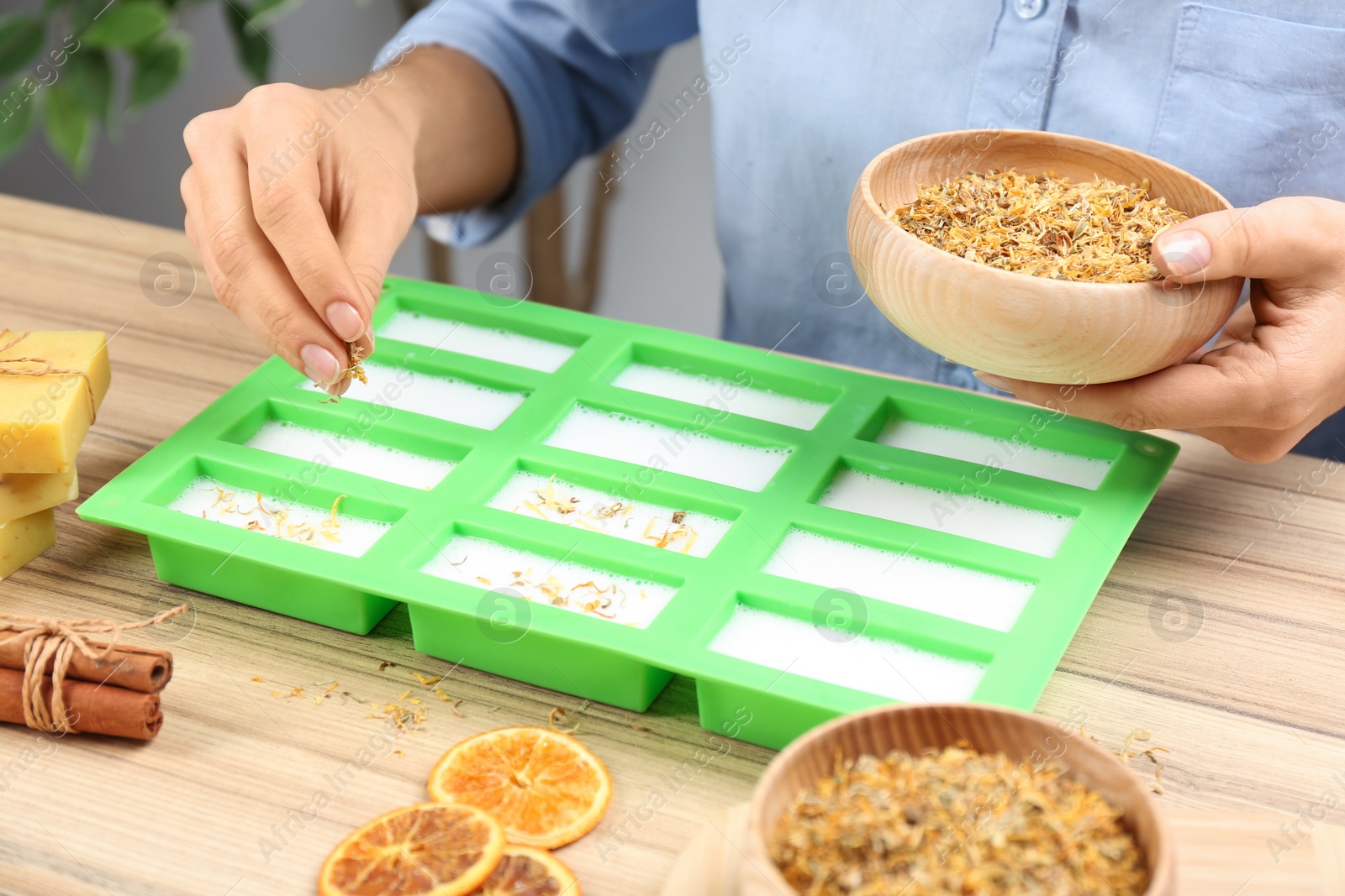 Photo of Woman making natural handmade soap at wooden table, closeup