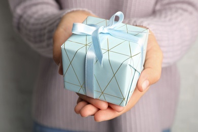 Photo of Young woman holding Christmas gift, closeup view