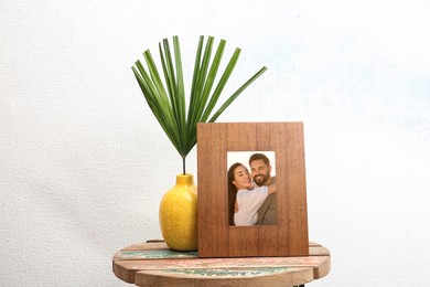 Portrait of happy young couple in photo frame on table near white wall