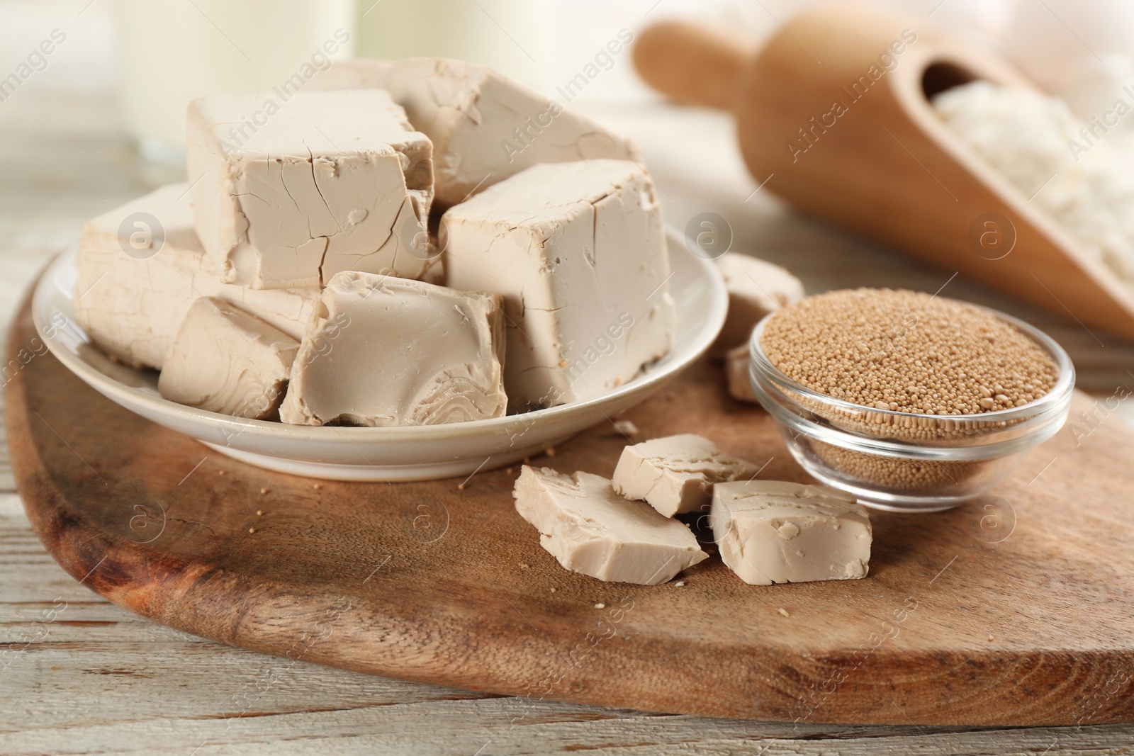 Photo of Compressed and granulated yeast on wooden board, closeup