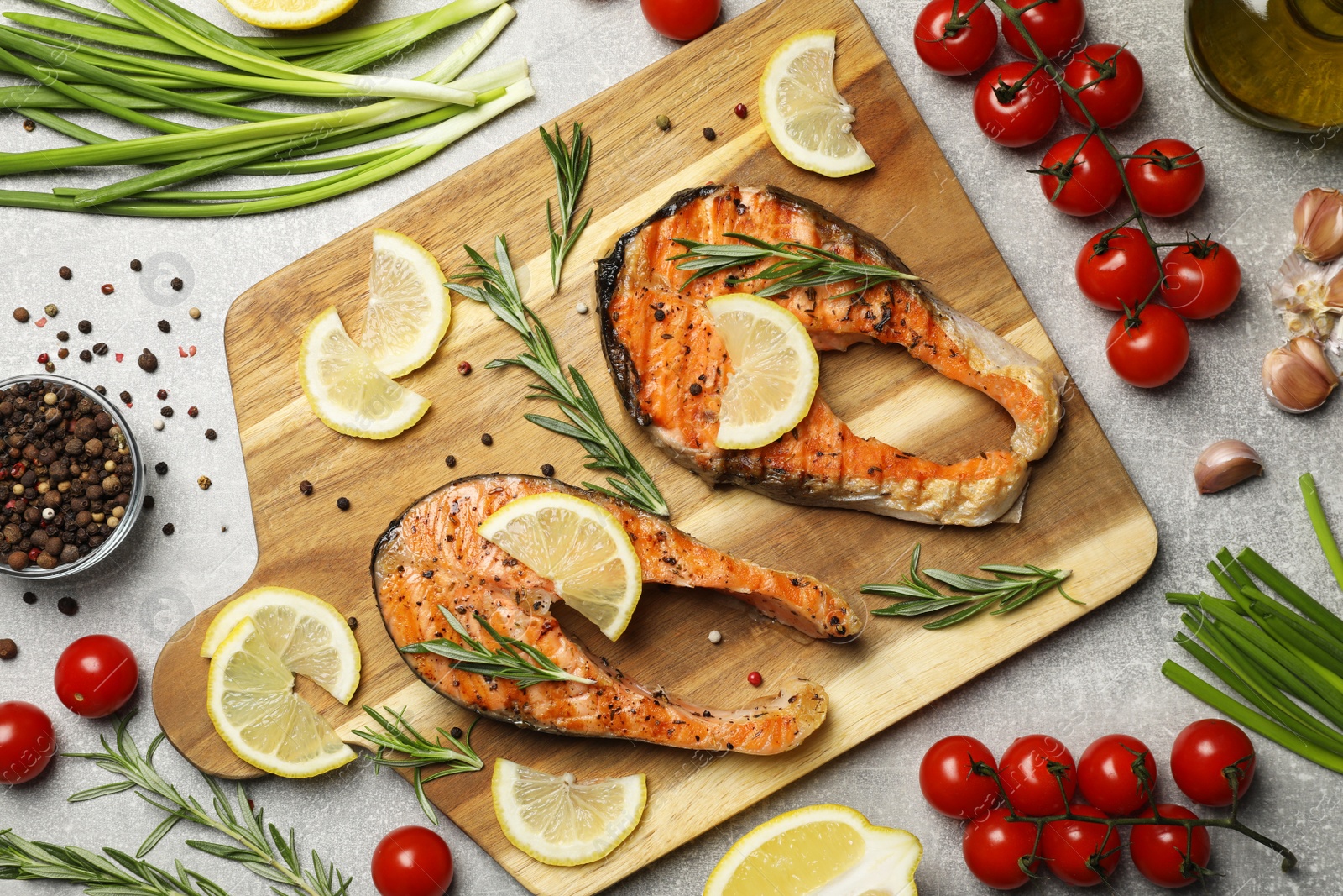 Photo of Tasty grilled salmon steaks and different ingredients on light grey table, flat lay