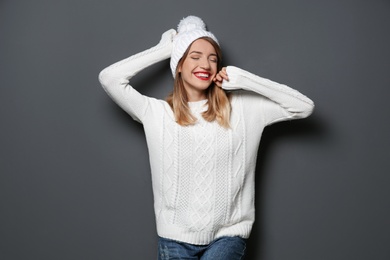 Photo of Beautiful young woman in warm sweater with hat on dark background