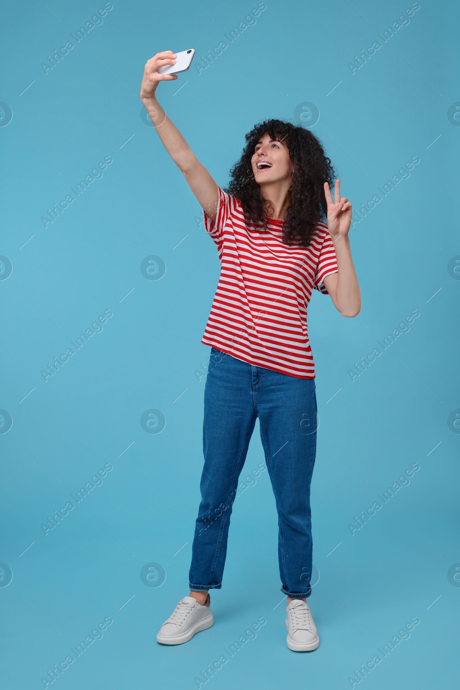 Photo of Beautiful young woman taking selfie on light blue background