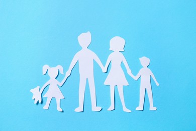 Photo of Paper family figures on light blue background, top view