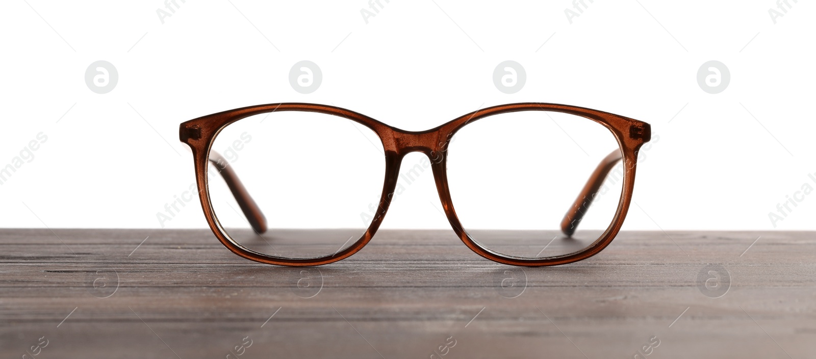 Photo of Stylish glasses with brown frame on wooden table against white background