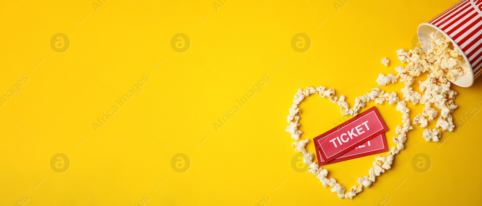 Image of Cinema tickets and heart made of popcorn on yellow background, flat lay with space for text. Banner design