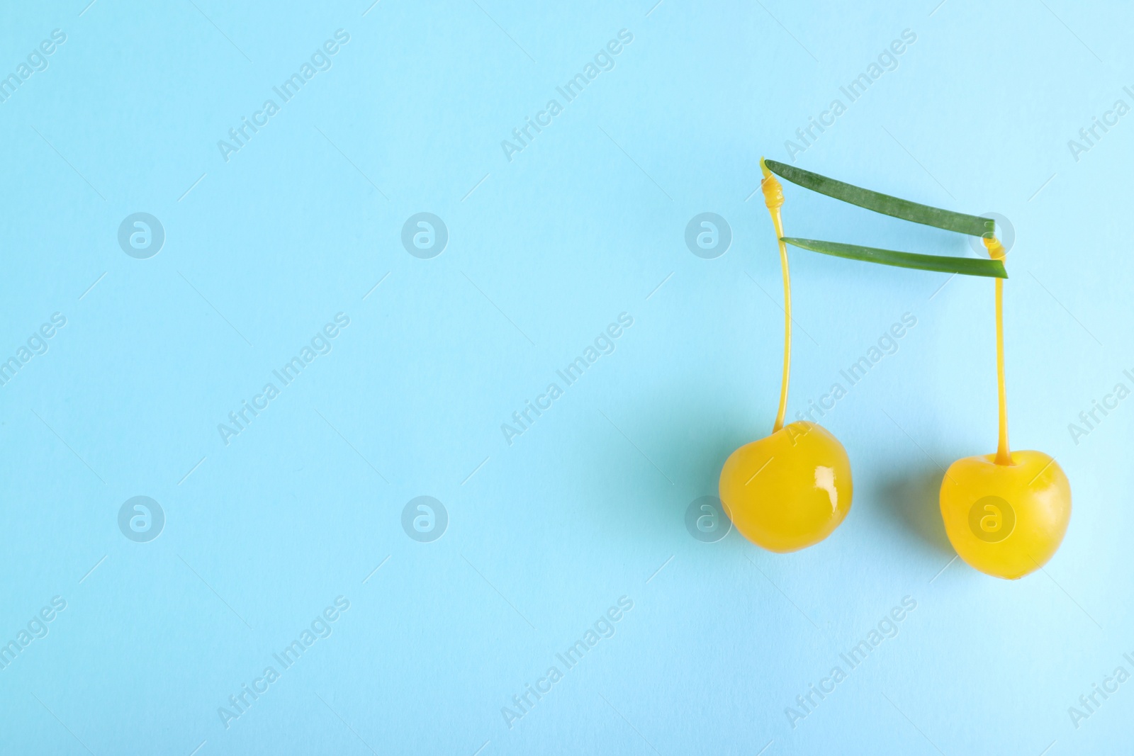 Photo of Musical note made of onion and cocktail cherries on color background, top view. Space for text