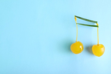 Photo of Musical note made of onion and cocktail cherries on color background, top view. Space for text