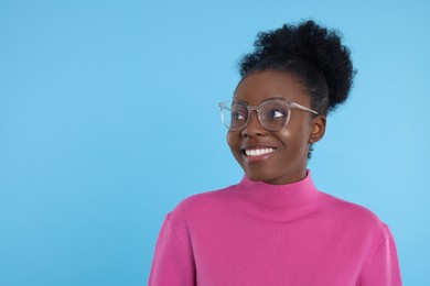 Photo of Portrait of beautiful young woman in eyeglasses on light blue background. Space for text