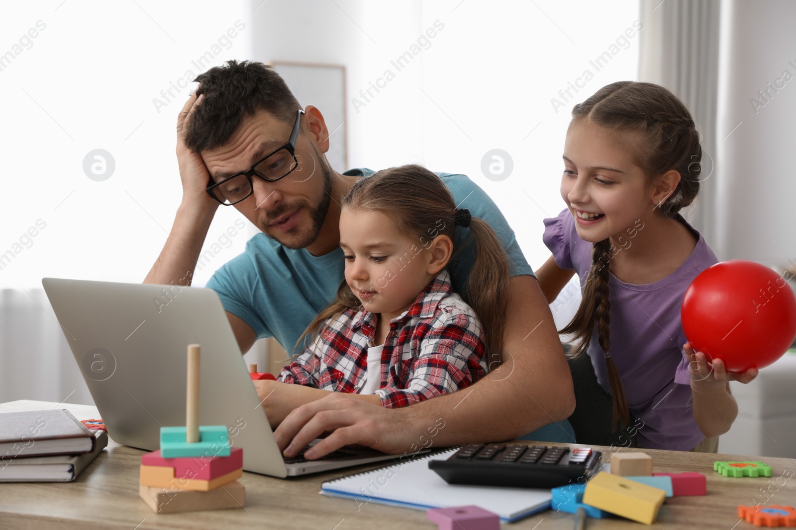 Photo of Children disturbing stressed man in living room. Working from home during quarantine