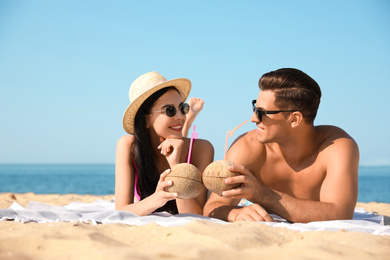 Photo of Happy couple with cocktails on sunny beach at resort