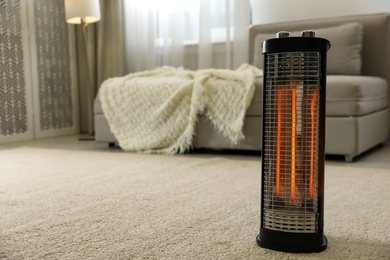 Photo of Modern electric halogen heater on floor in living room interior