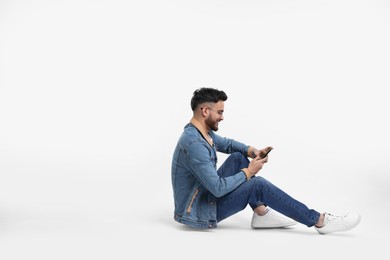 Photo of Handsome man using smartphone on white background, space for text