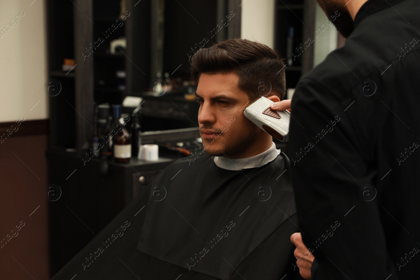 Photo of Professional hairdresser making stylish haircut in salon, closeup