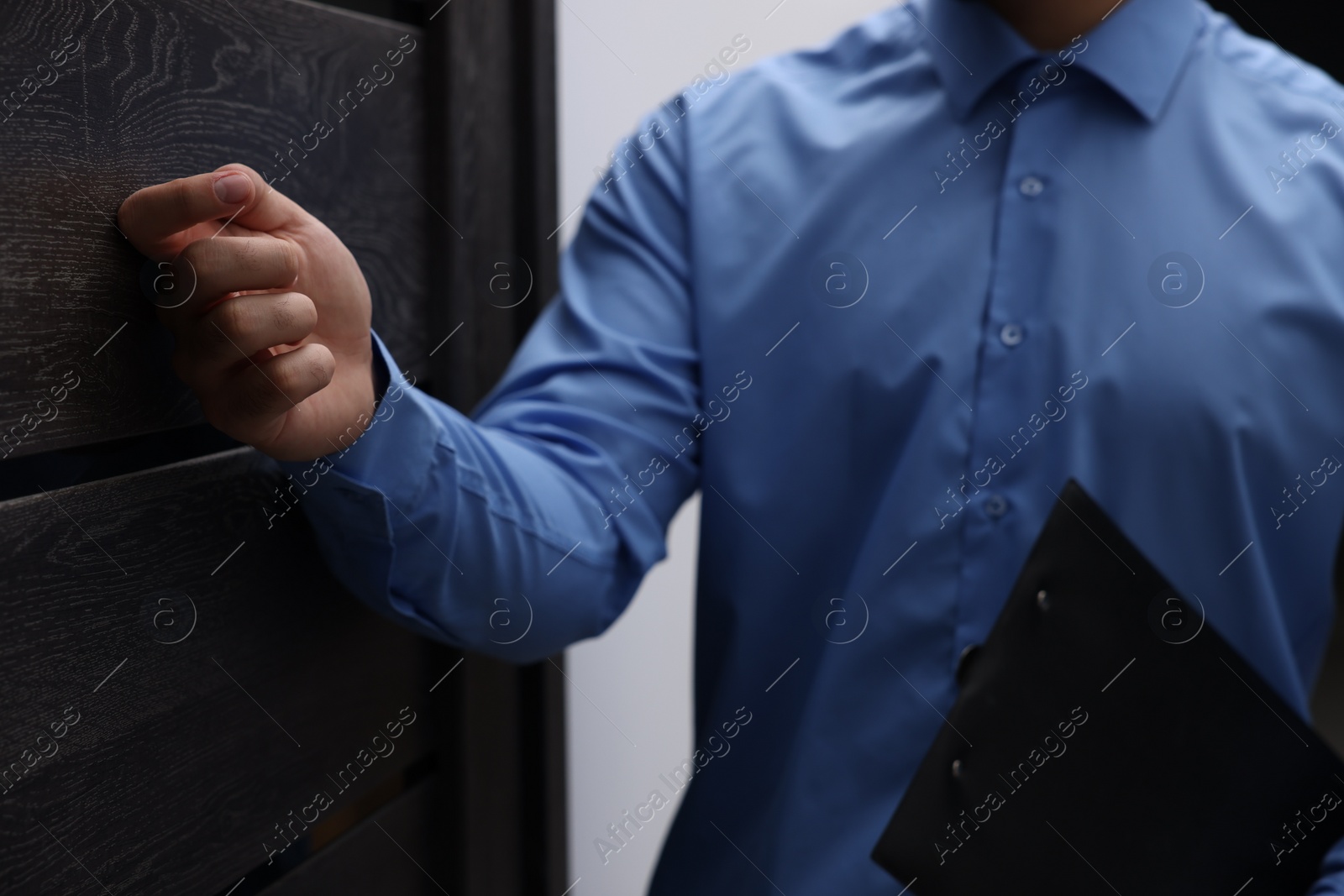 Photo of Collection agent with clipboard knocking on wooden door, closeup