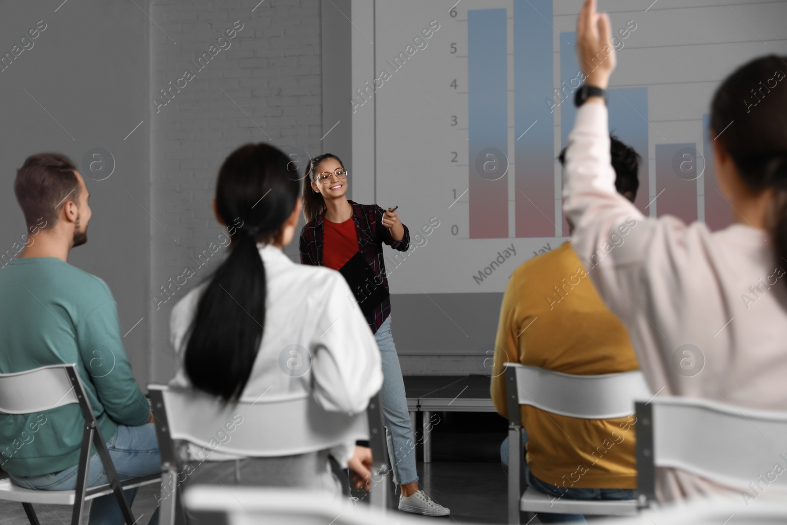 Photo of Female business trainer giving lecture in conference room with projection screen