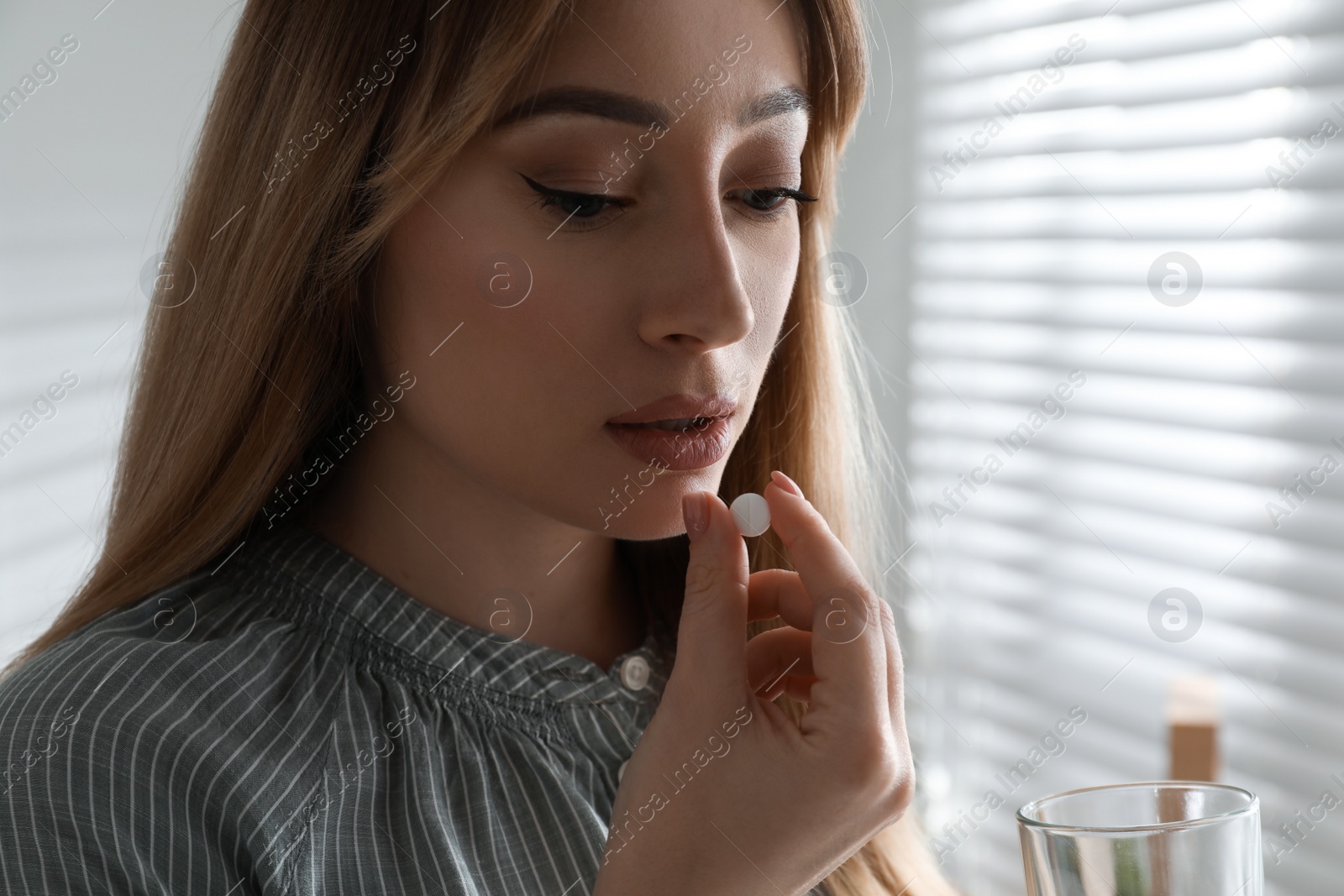 Photo of Young woman taking abortion pill indoors, closeup