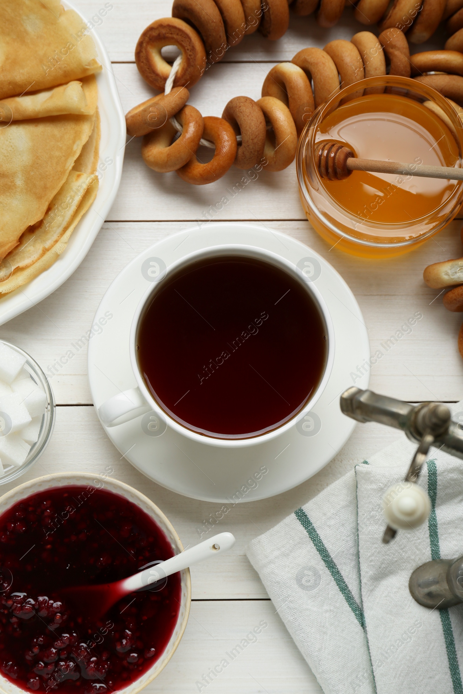 Photo of Metal samovar with cup of tea and treats on white wooden table, flat lay