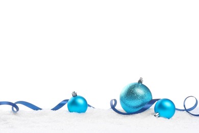 Photo of Beautiful light blue Christmas balls and ribbon on snow against white background